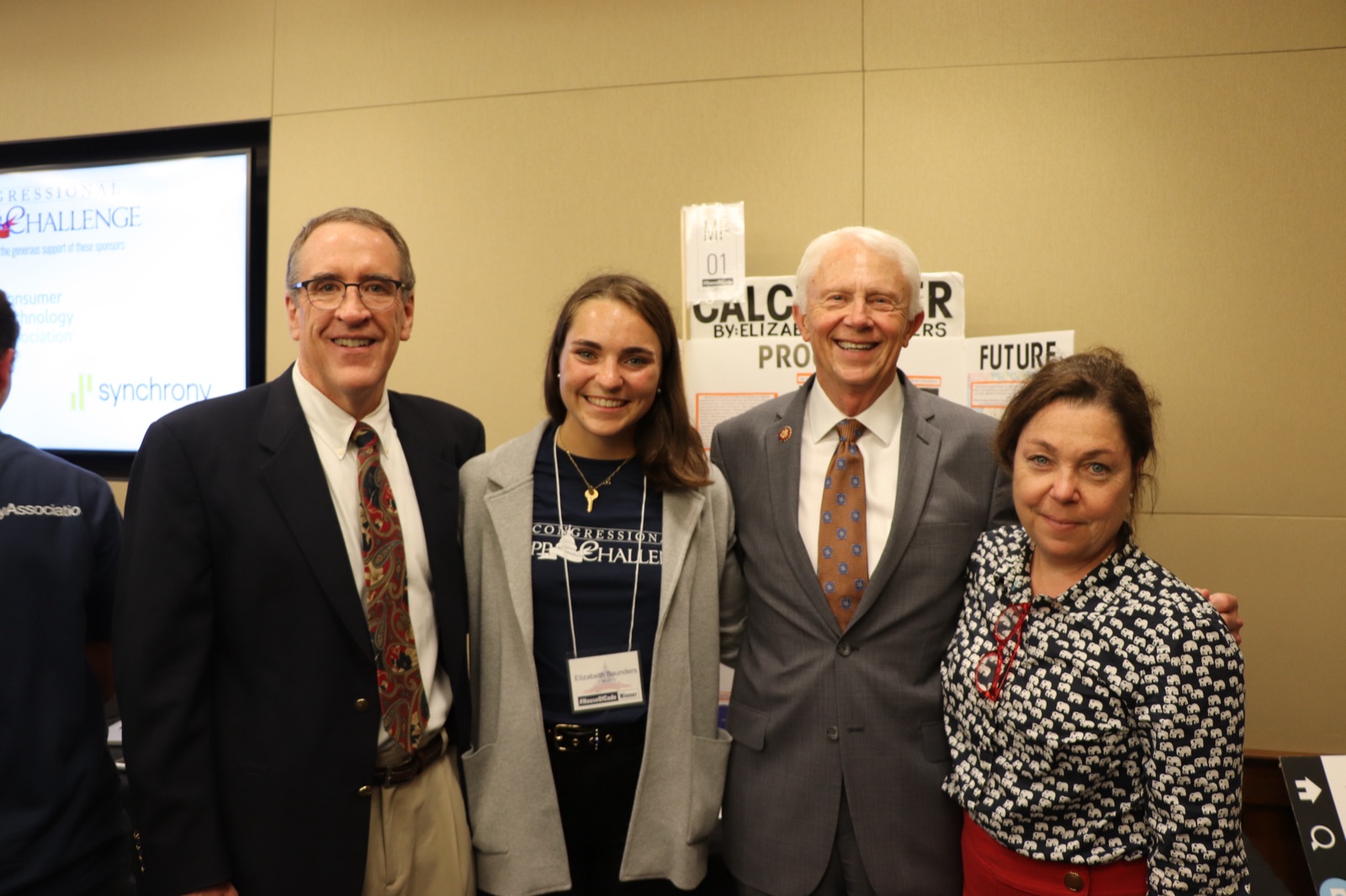 Elizabeth Saunders with her CalcuSaver display and members of Congress, wearing a House of Code Winner badge
