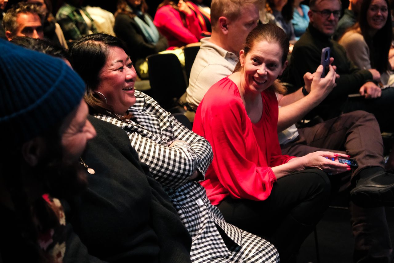 Community members smiling and taking photos during a Give5 Mile High presentation